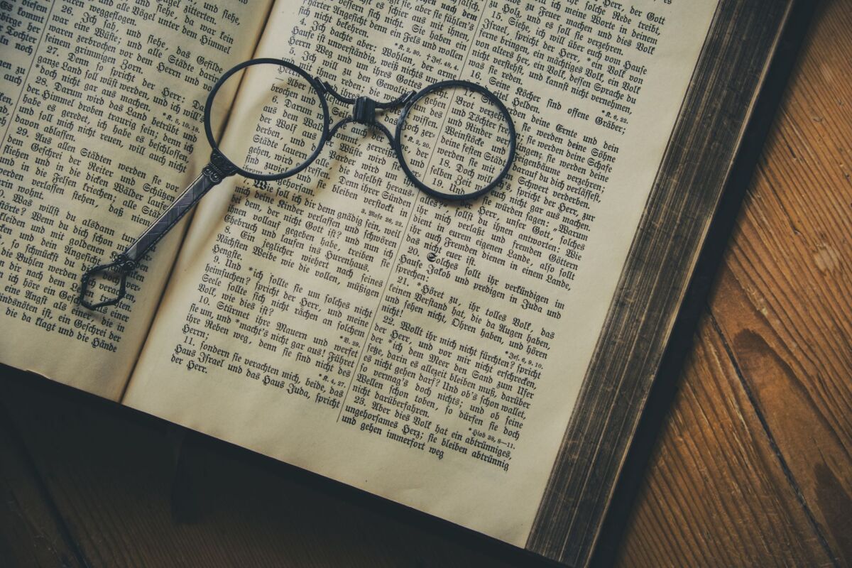 A vintage book with old-fashioned spectacles resting on its pages, symbolizing knowledge and history.